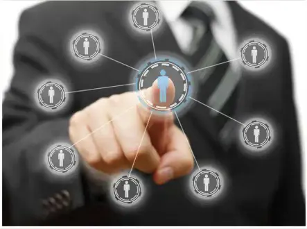 A businessman's hand points to a digital network of connected people, illustrating connection or staffing resources.