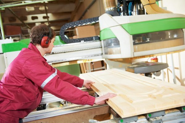 A woodworking professional uses a CNC machine to process a wood product.